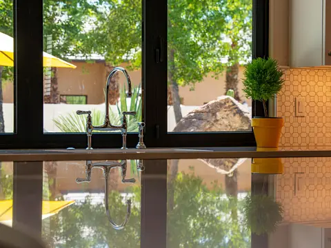 A kitchen tap by a sunny window with a potted plant on the counter