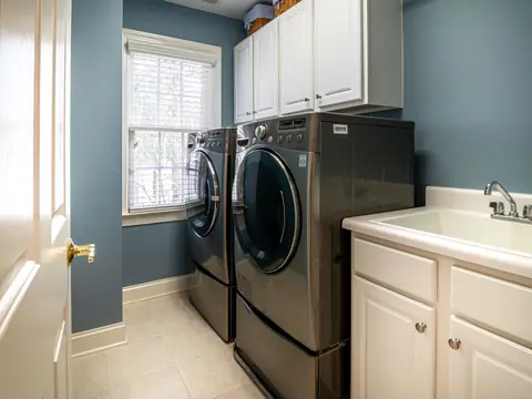A bright laundry room with a washer, a dryer and a utility sink