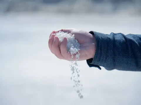 Coarse white salt poured from a hand