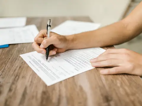 Filling in a paper form with a pen at a table
