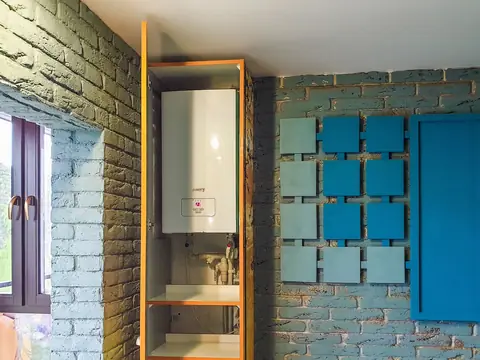 A wall-mounted water heater fitted in a small utility nook