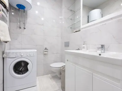 A bathroom with a wall-mounted water heater above the washing machine
