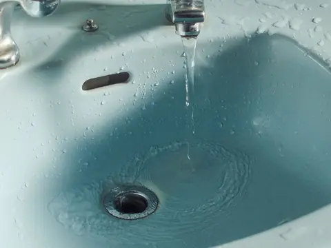 Water running from a tap into a blue basin
