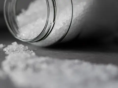 Coarse salt pouring from a glass jar