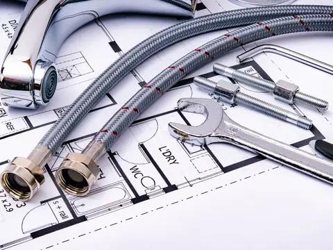 Braided steel hoses, fittings and wrenches on a plumbing plan