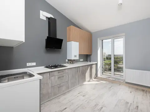 A bright kitchen with a sink, a cooktop and a wall-mounted water heater
